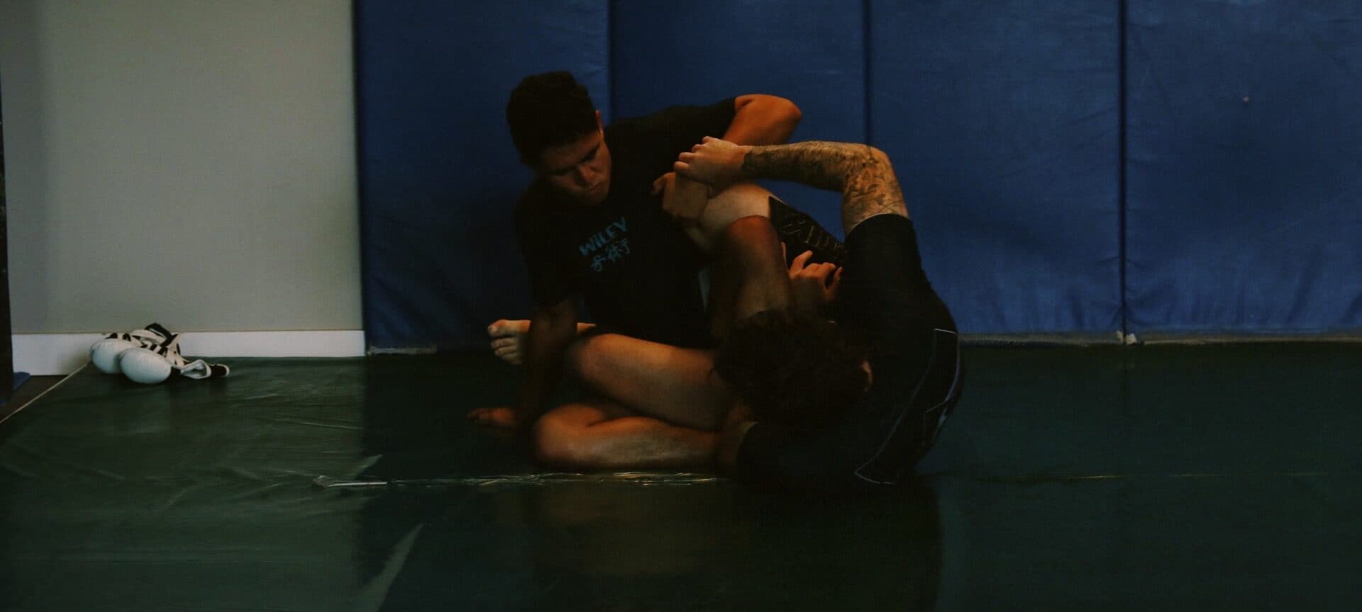 A pair of students rolling on the open training floor at Wiley Jiu-Jitsu YYC in Calgary